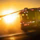 A photo of the sun setting behind the LAFD's electric fire truck as it sprays water out a cannon.